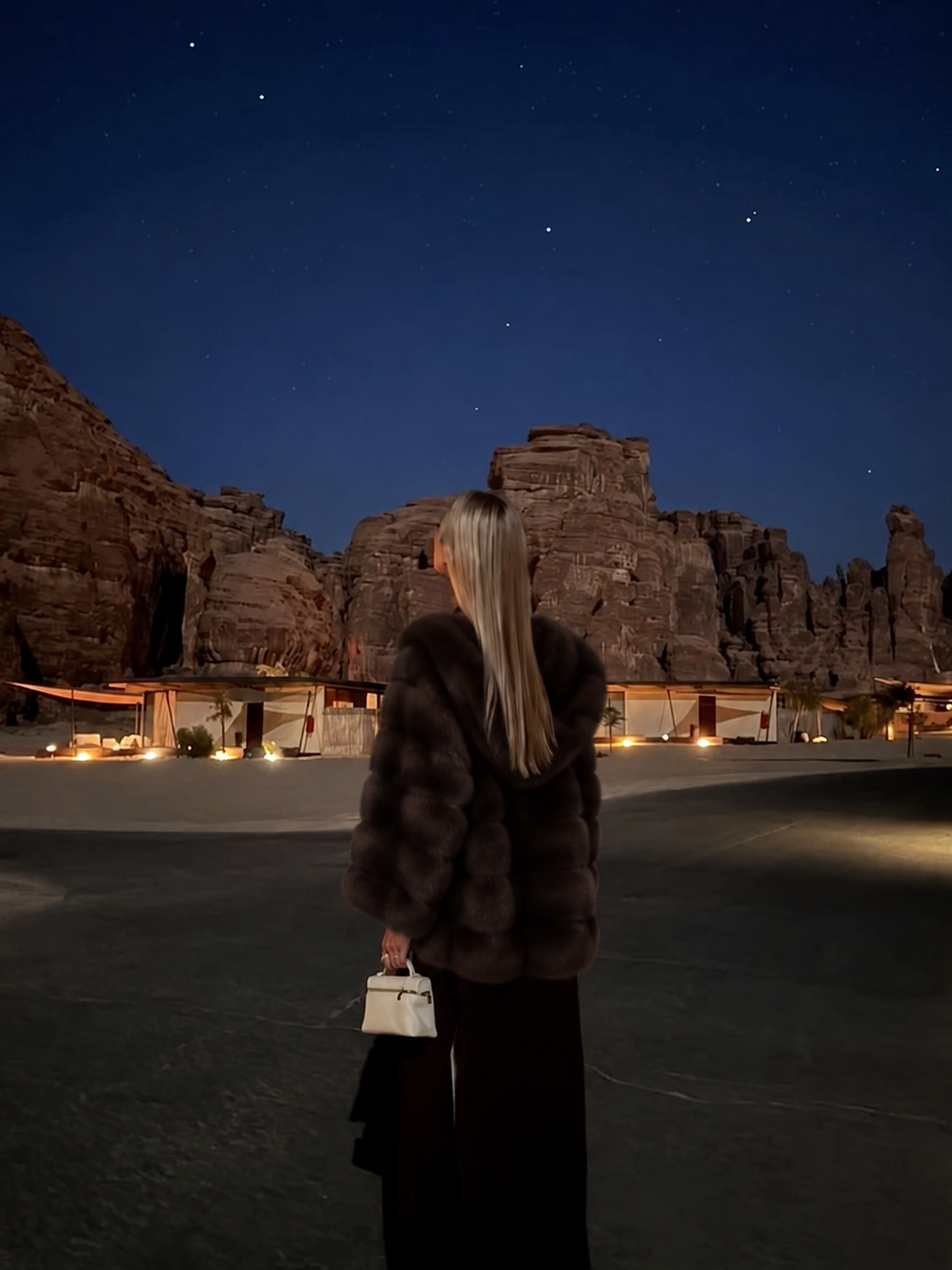 Woman in luxury sable fur coat standing under a starry desert sky