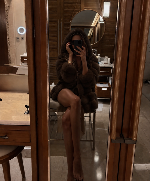 Mirror selfie in fur coat at luxury hotel bathroom
